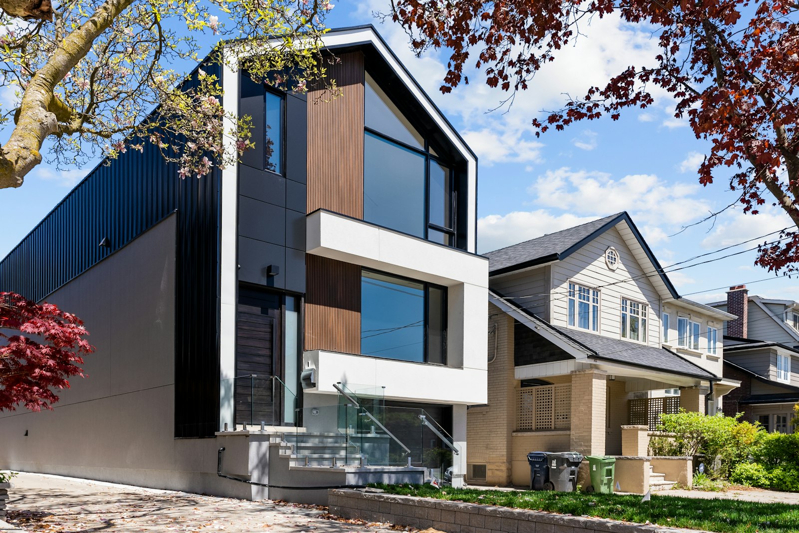 Façade contemporaine en métal sombre à côté d’une maison traditionnelle
